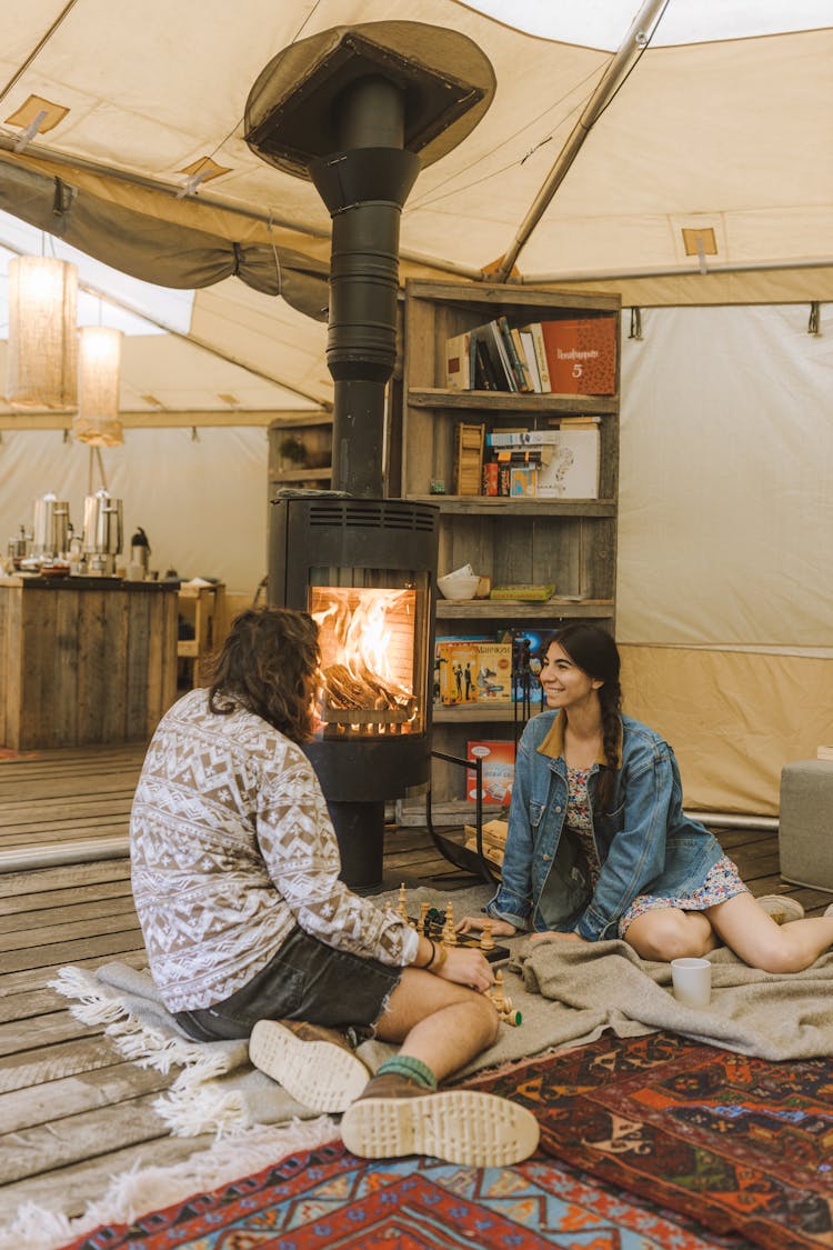 A Couple Sitting In A Tent By The Fireplace