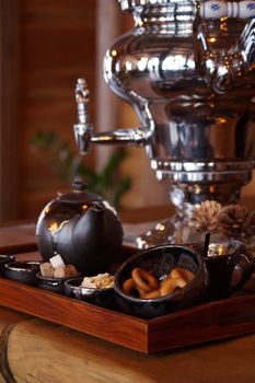 Warm, inviting scene of a traditional Russian samovar with tea and snacks on a wooden tray.