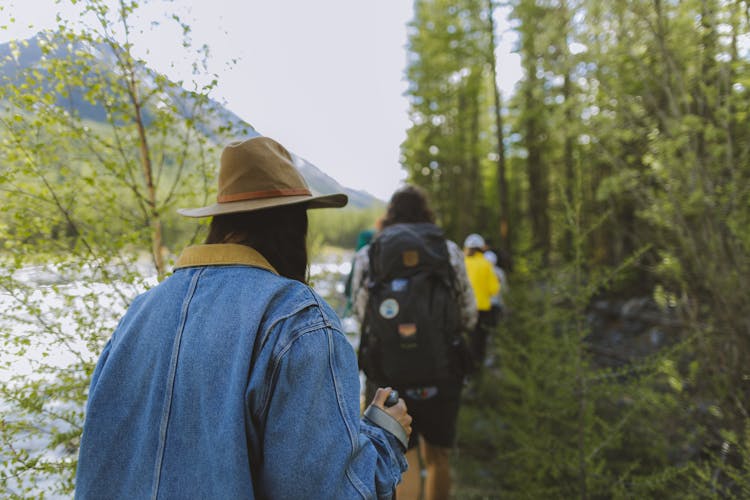 Group Of People Walking By The Trees And River