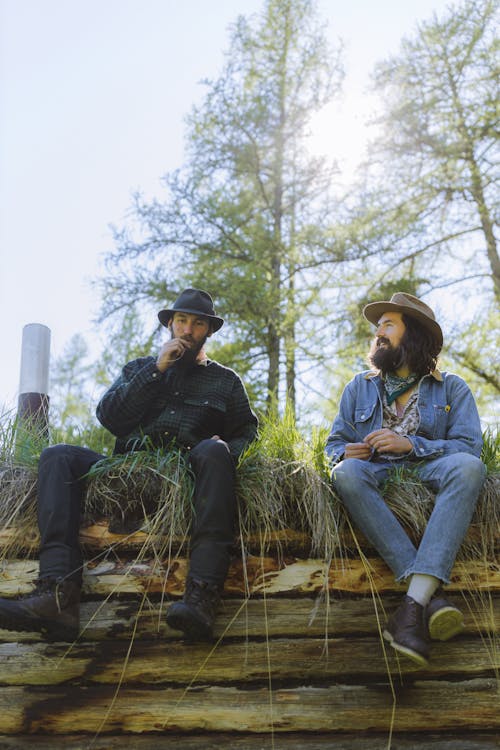 Two Men in Hats Sitting on a Wooden Bench in a Park