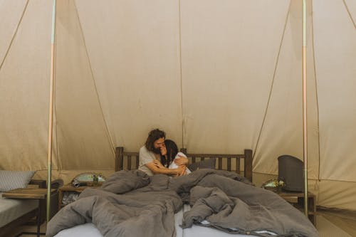 Free Man Hugging a Woman in Bed Inside a Tent Stock Photo