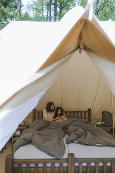 Couple enjoying a peaceful morning in a glamping tent surrounded by nature.