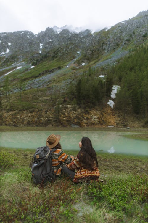 Free Couple Sitting on Green Grass Field Near Lake Stock Photo
