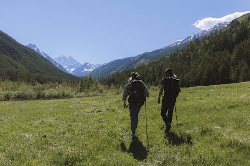 Men Walking on Grassland Near the Mountains