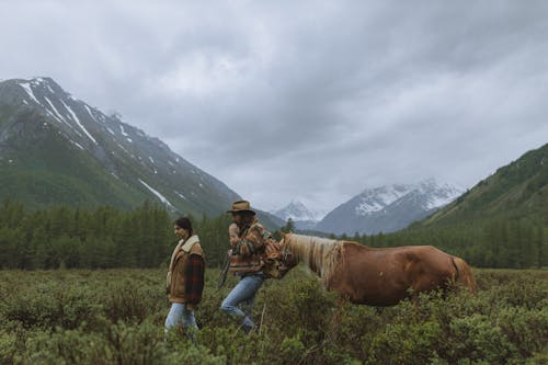 Woman and Man Walking with a Horse on Grassland