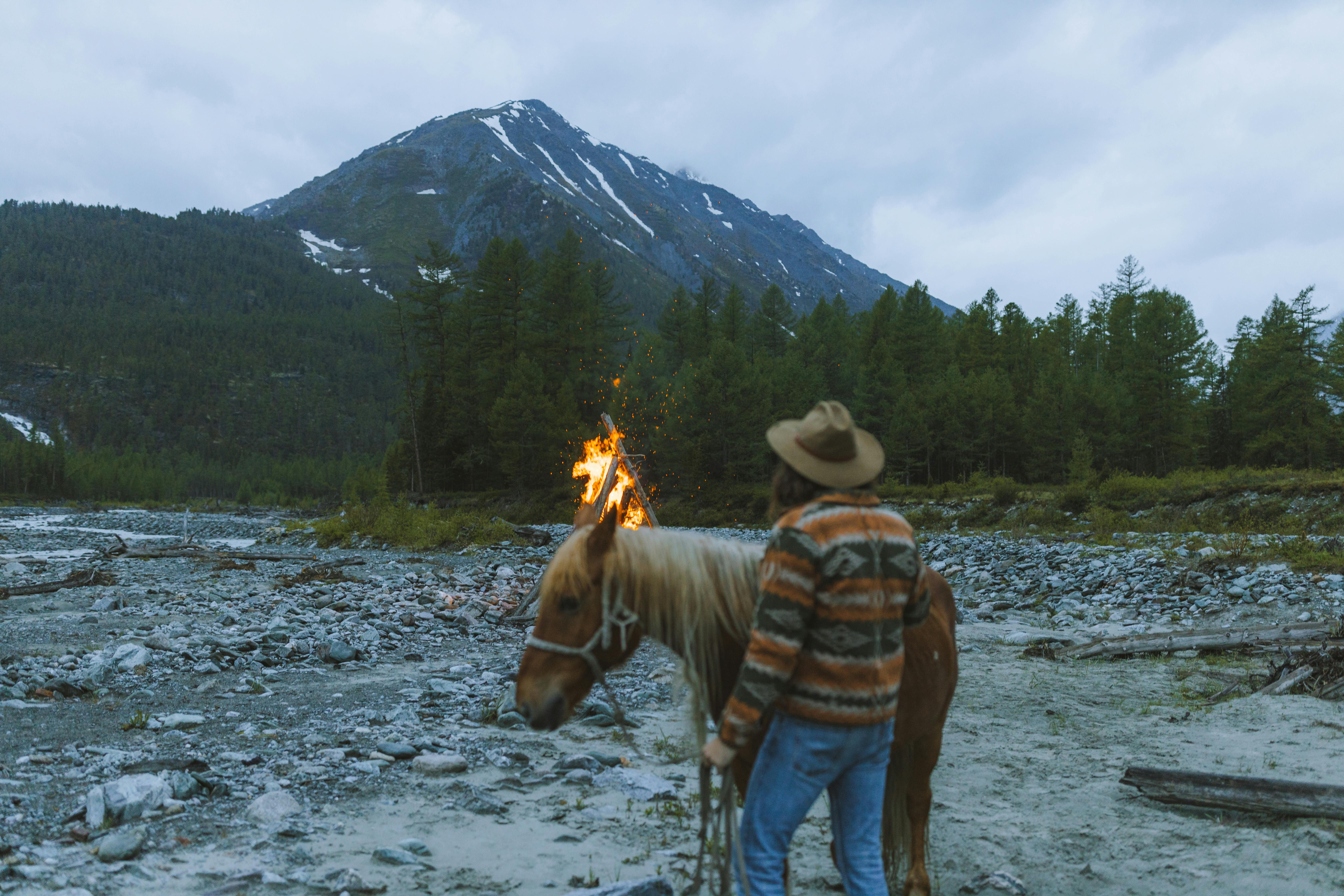 man holding horse standing near the bonfire