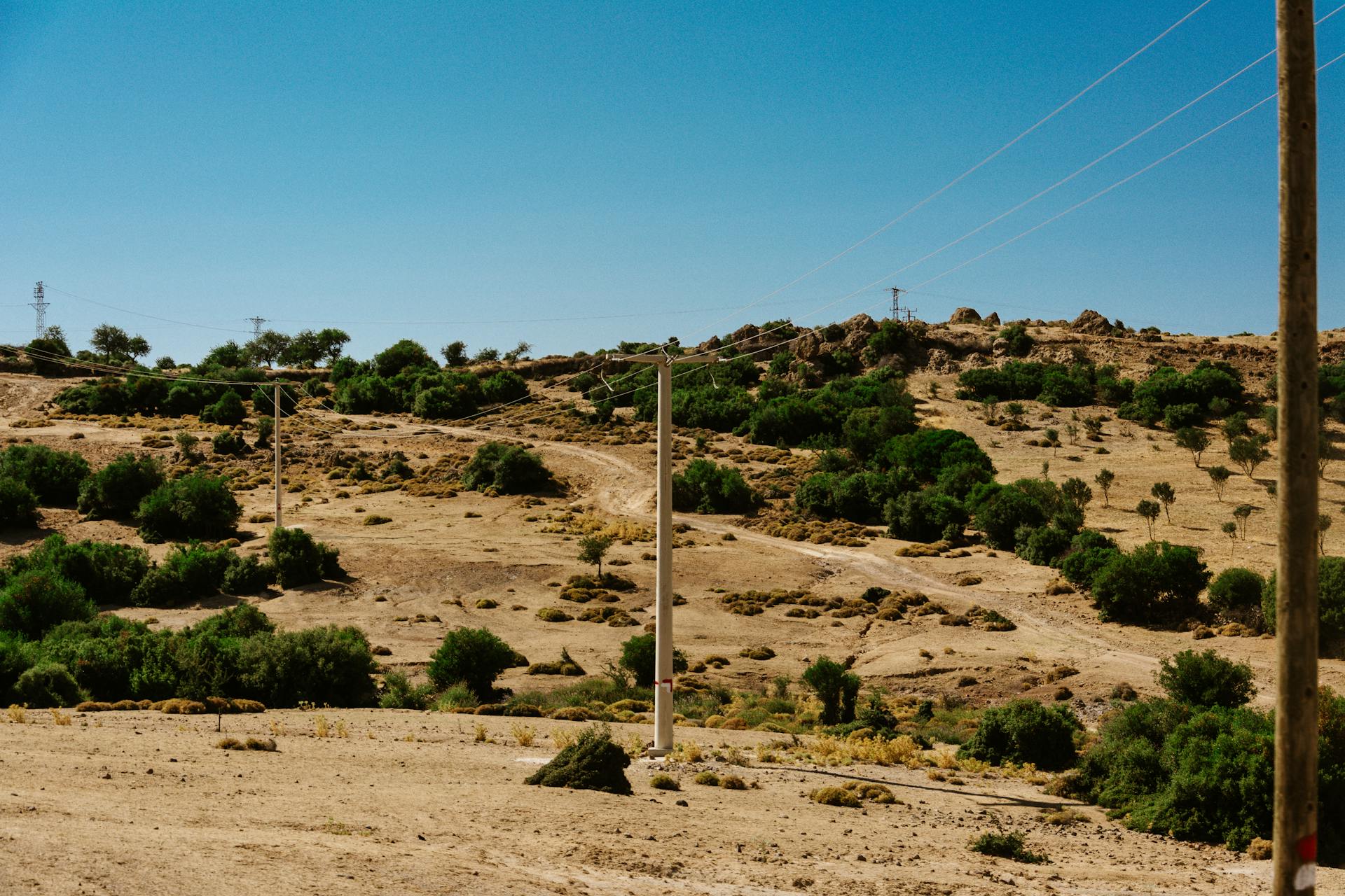 Vast desert terrain with sparse greenery and power lines stretching across the horizon.