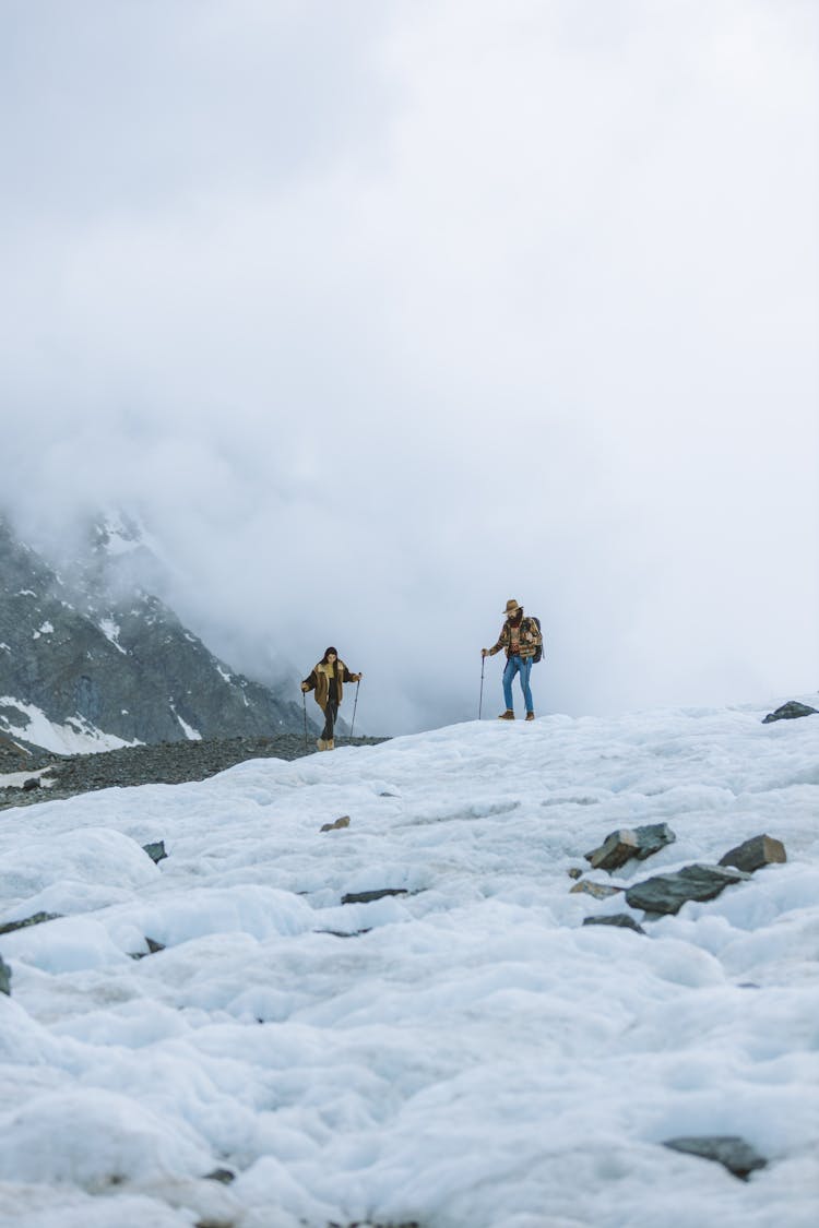 A Couple Hiking On Snow Covered Mountain