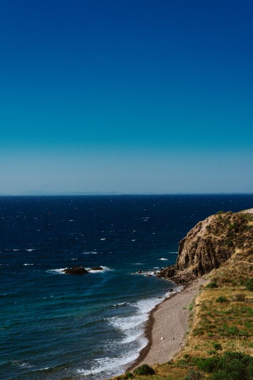 Free Breathtaking coastal view featuring a rocky cliff, horizon, and deep blue ocean with waves. Stock Photo