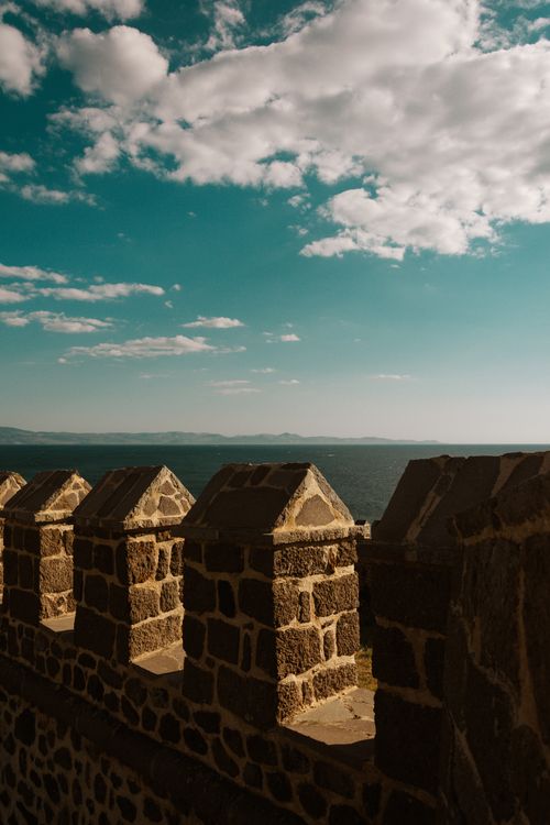 Free Captivating view of a historic stone wall against a blue sky and ocean, captured during a scenic sunset. Stock Photo