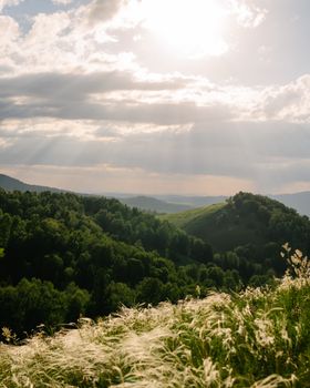 Breathtaking view of lush green mountains under a dramatic sunset sky. Perfect for nature lovers.