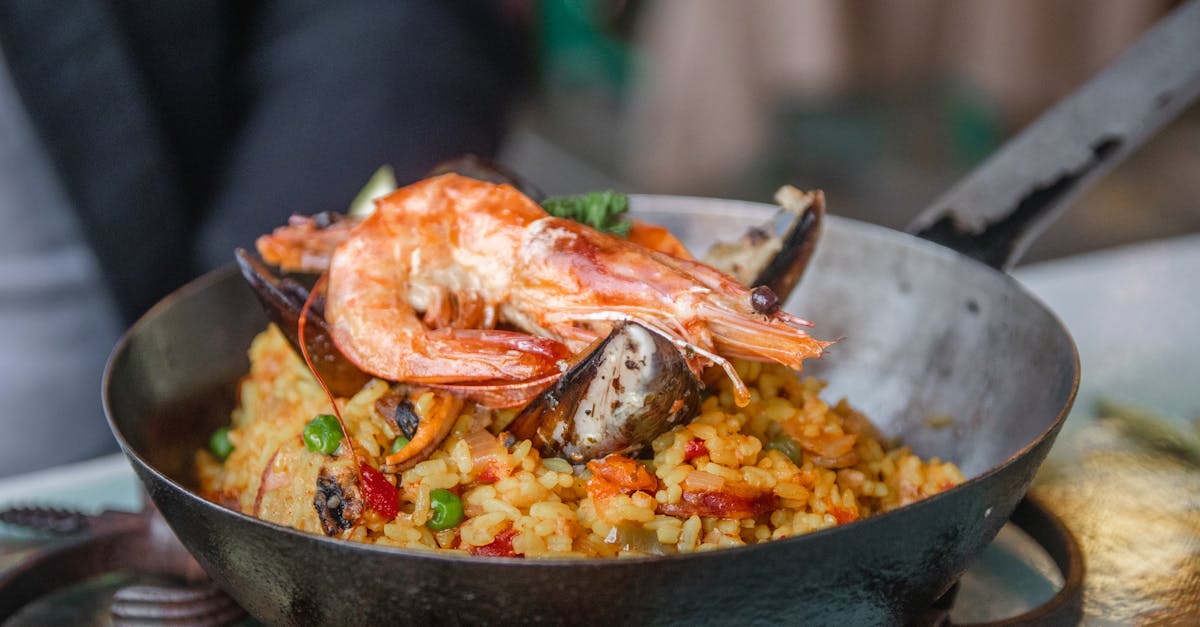 A display of various fresh Spanish ingredients like tomatoes, peppers, and herbs on a wooden table.