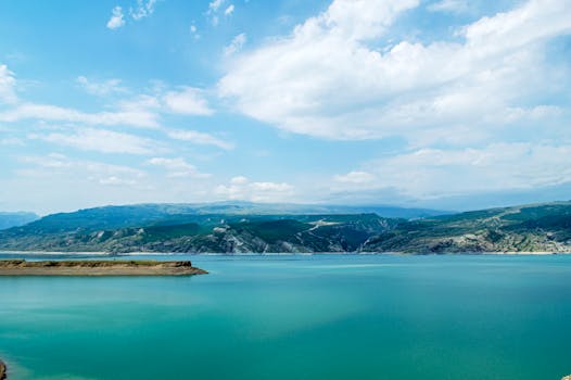 A stunning seascape showcasing turquoise waters and rolling hills under a bright sky.