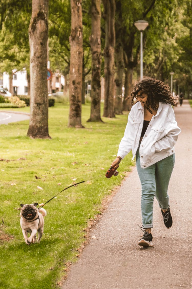 A Woman Running At A Park With Her Dog 