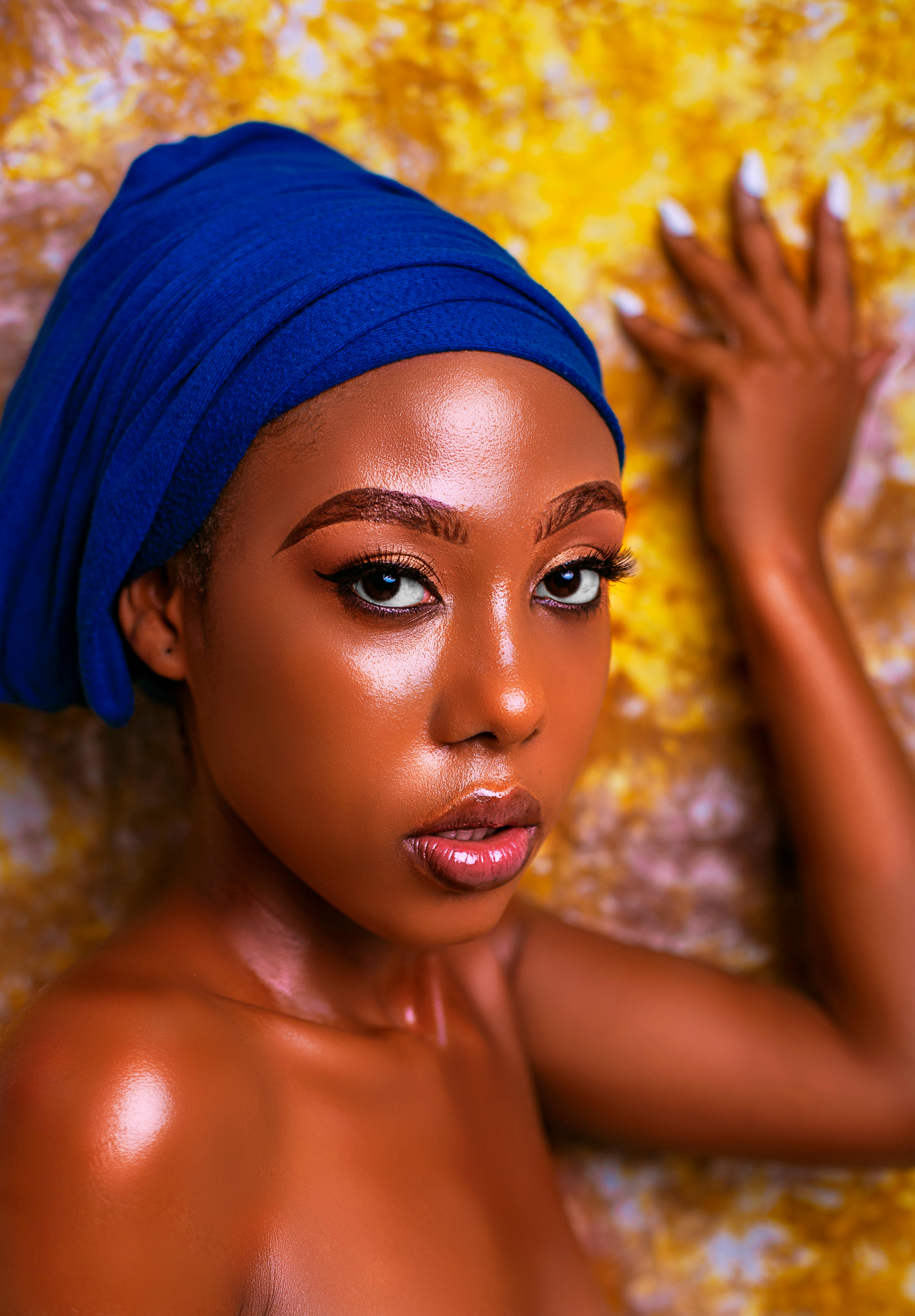 Vibrant portrait of a woman in a striking blue headdress against a textured backdrop.