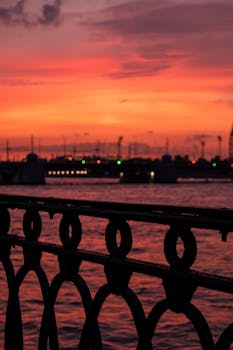 Dramatic silhouette of harbor and railings against a vibrant sunset in St. Petersburg, Russia.