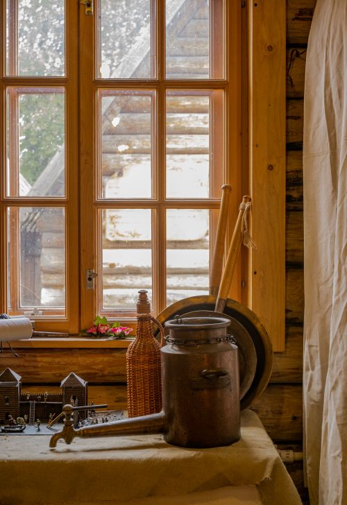 Free Cozy rustic interior featuring vintage metalware and wooden elements by a window in a cabin setting. Stock Photo