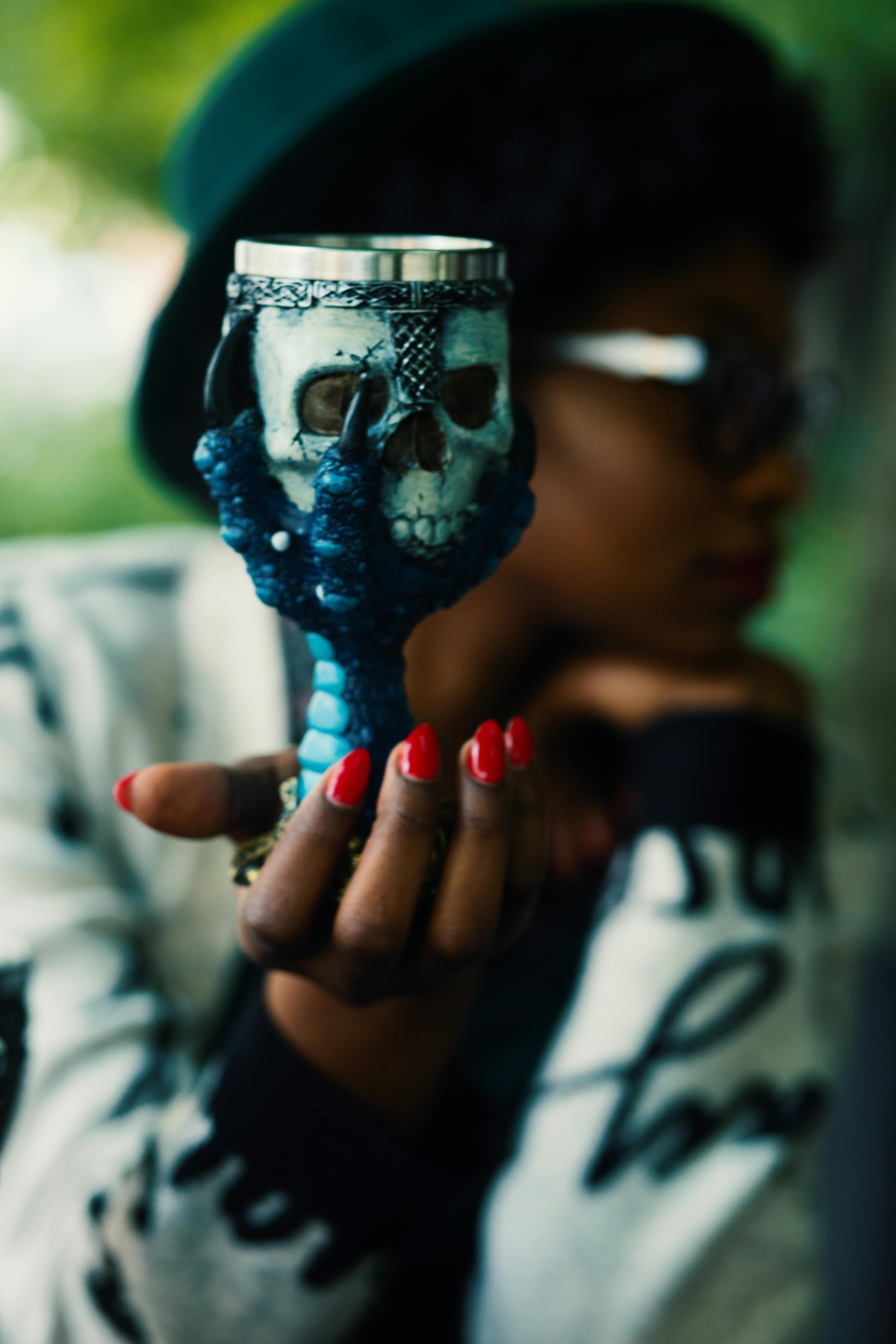 person holding skull and bird claw goblet