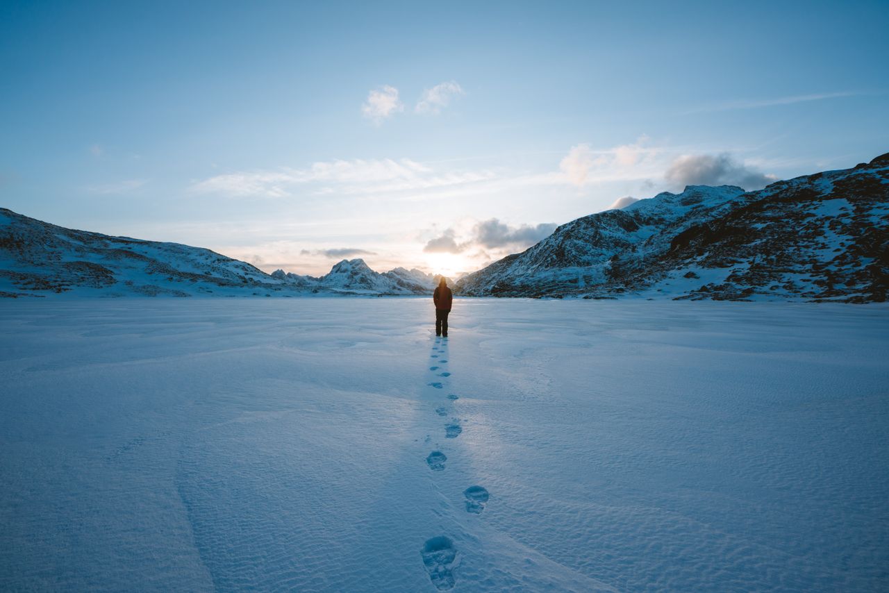 a person walking alone on a snowy landscape in flakstad norway during