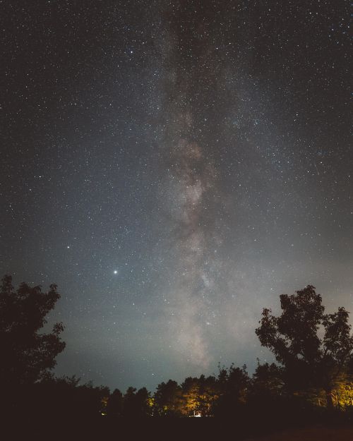 Free Stunning view of the Milky Way galaxy above a serene forest landscape. Stock Photo