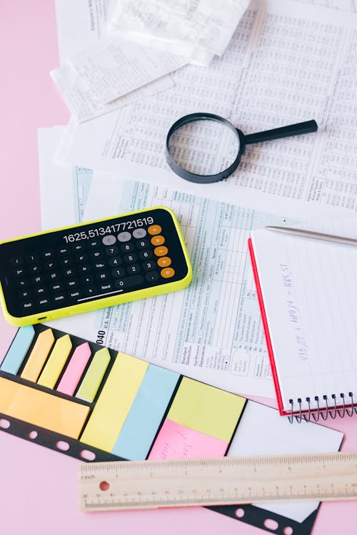  Magnifying Glass on White Papers Beside a Calculator