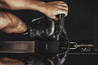 特写镜头中，一名男子在室内使用赛艇机，重点展示鞋类和设备