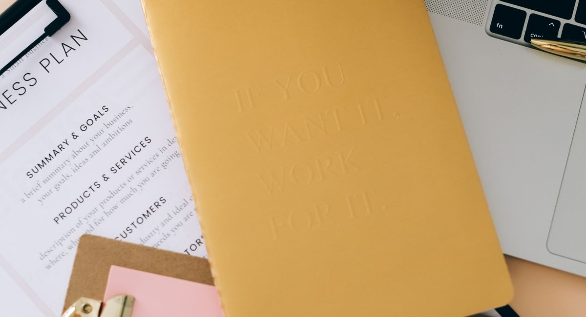 Clipboards, stationery and a laptop arranged on a desk
