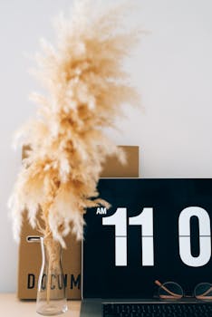 Contemporary office with digital clock screensaver and decorative pampas grass.