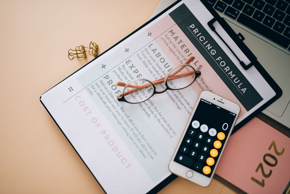 Vue de dessus d'un espace de travail avec calculatrice, documents financiers et stylo sur un bureau.