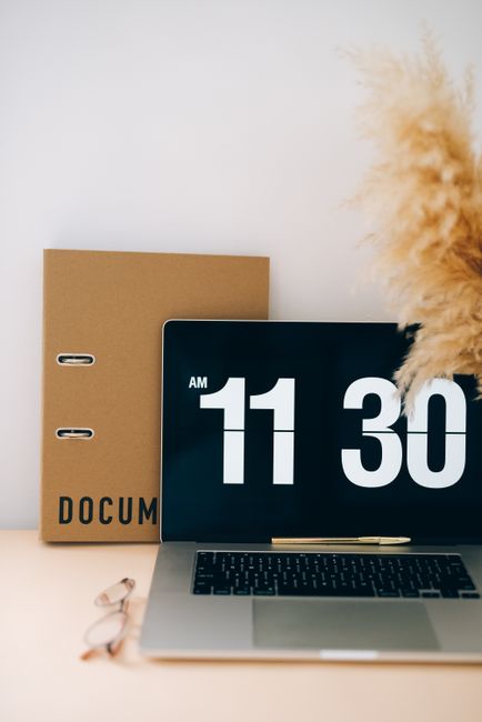 A stylish desk with a laptop showing 11:30 AM, a ring binder