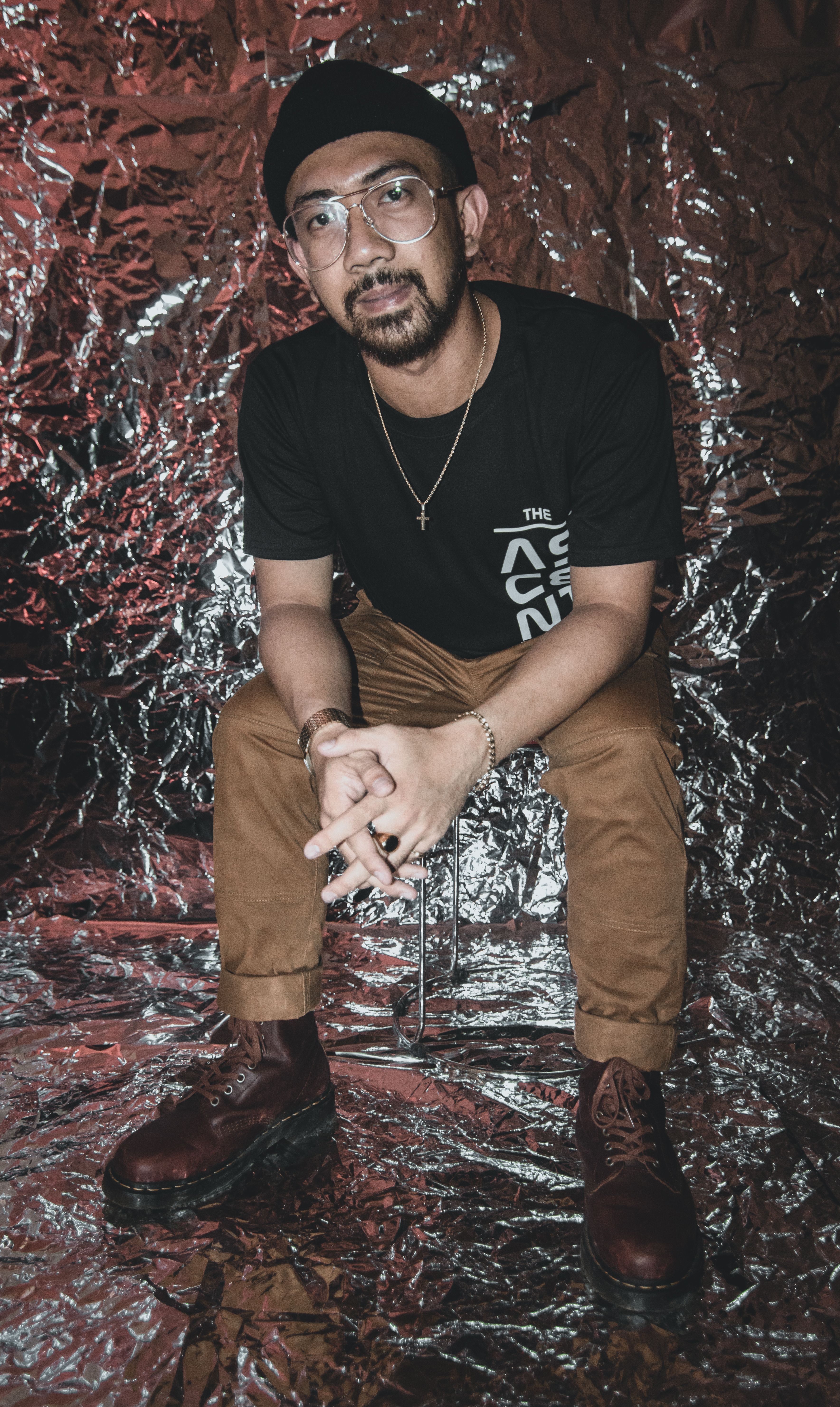 Portrait of a stylish man posing in trendy streetwear against a metallic foil backdrop.