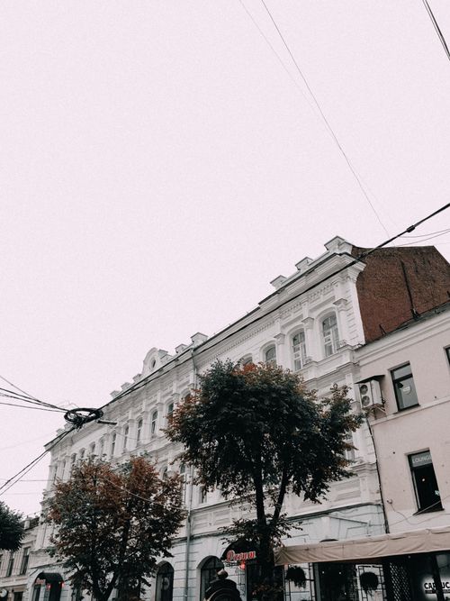 Free Low angle view of classic European-style buildings with trees and clouded sky. Stock Photo