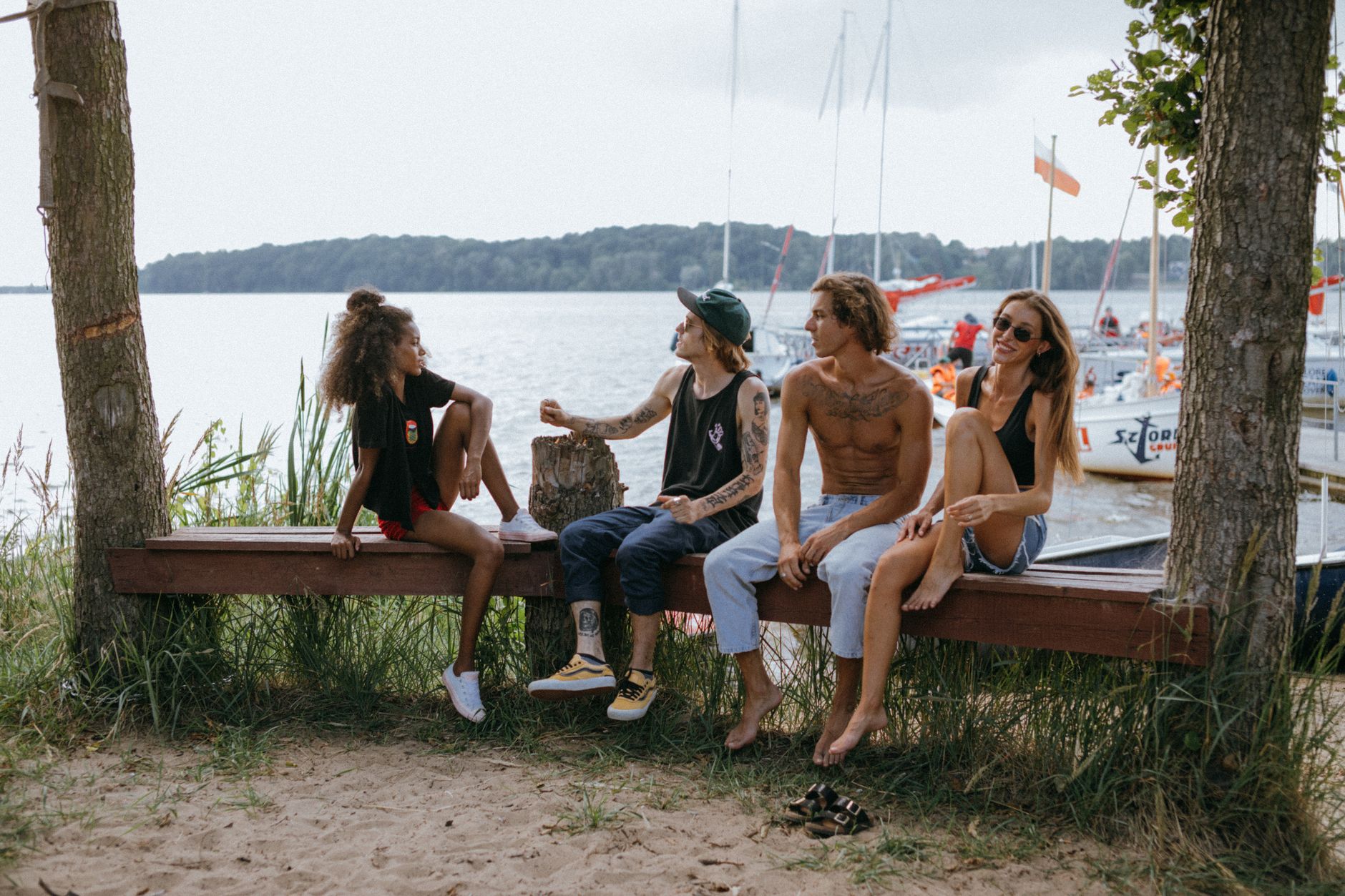 Groupe d'amis tatoués portant des tatouages temporaires visibles à la plage, ambiance lifestyle fun