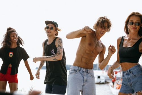 Free Energetic group of young adults dancing at a lively beachside party. Stock Photo