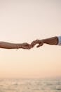 特写的夫妇手牵着手与海滩和日出的背景，象征着爱情