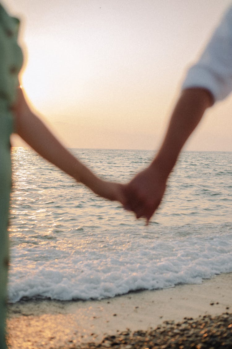 A Couple Holding Hands On The Beach