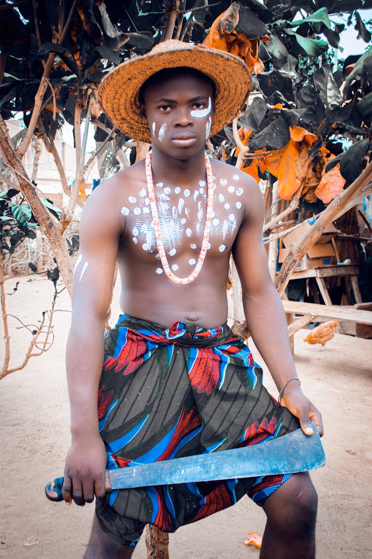 A Painted Man Holding A Jungle Bolo