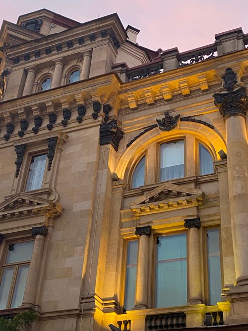 Free Elegant architectural details of a historic building's facade illuminated at sunset. Stock Photo