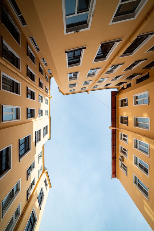 Free Looking up between tall urban buildings with clear sky above, creating a geometric symmetry. Stock Photo