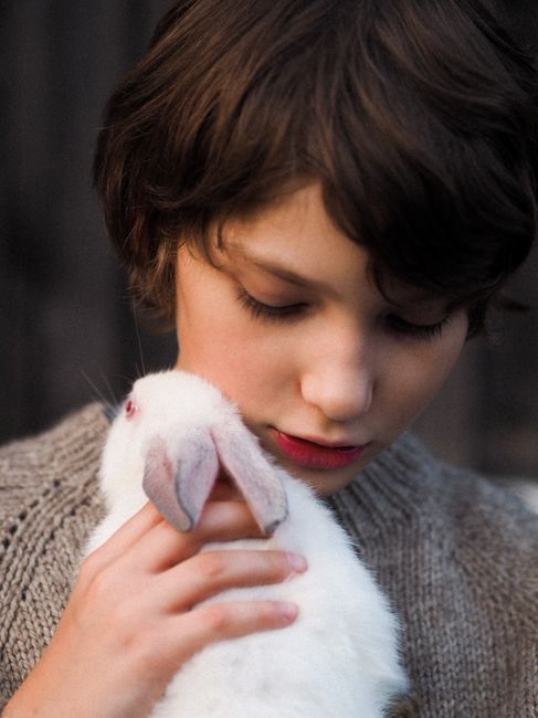 A young girl tenderly holds a white rabbit, showcasing a serene and intimate moment.