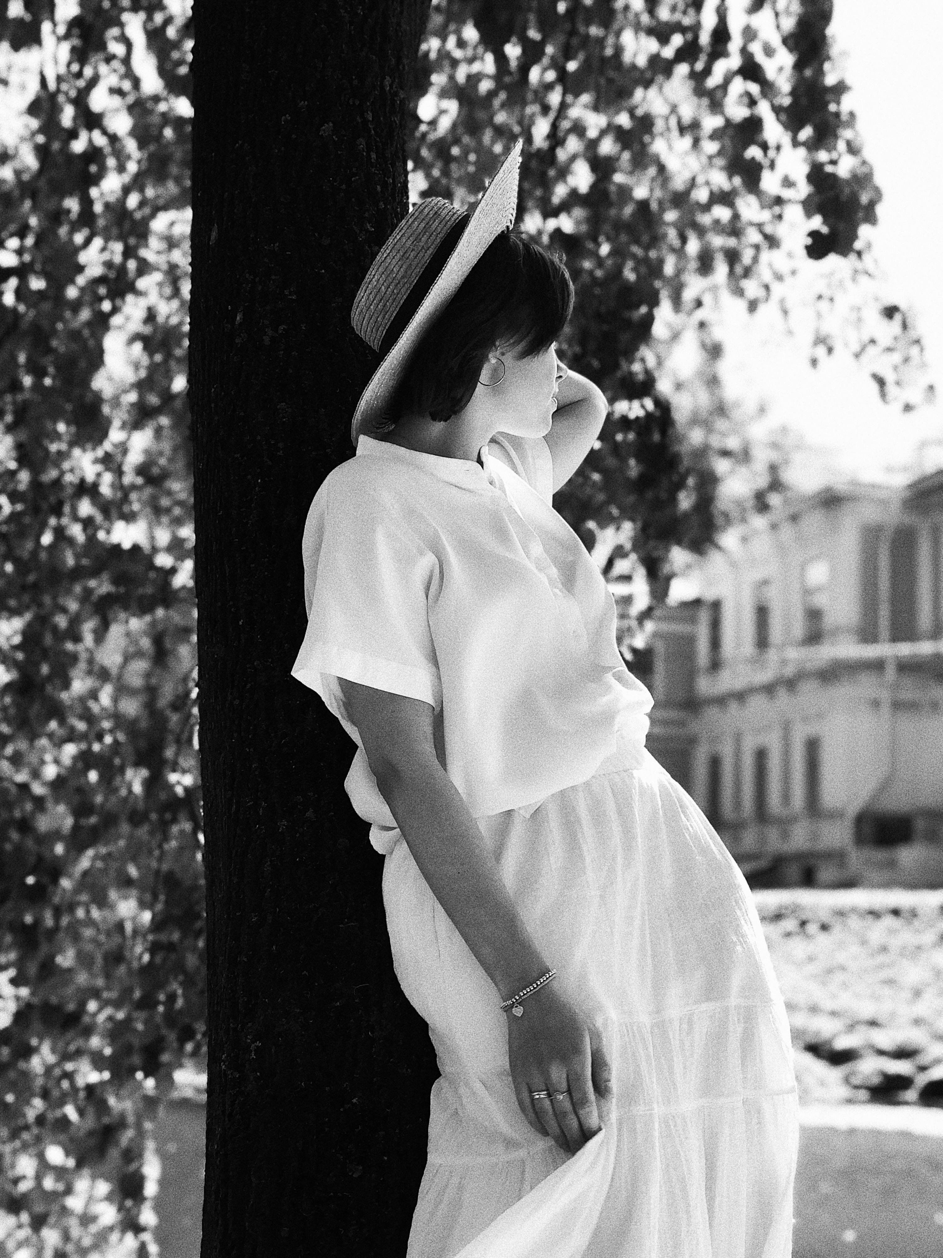 woman wearing a hat standing under a tree