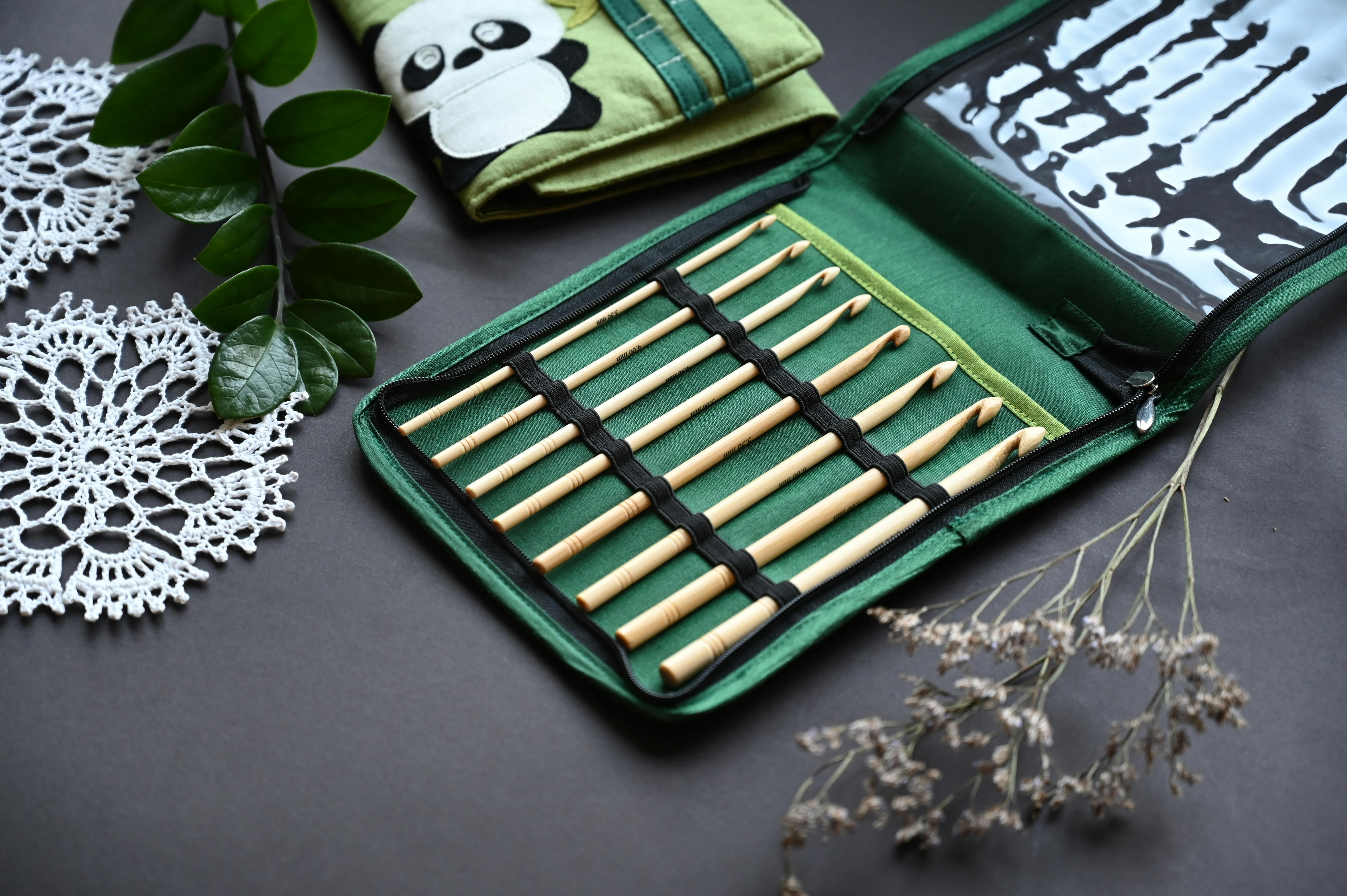 Stylish bamboo knitting needles in a green case with crochet doilies and leaves, perfect for crafters.