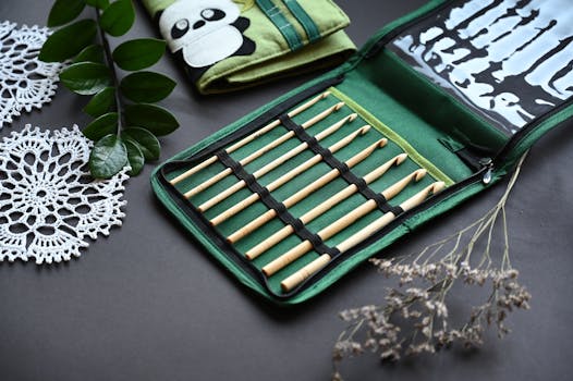 Stylish bamboo knitting needles in a green case with crochet doilies and leaves, perfect for crafters.