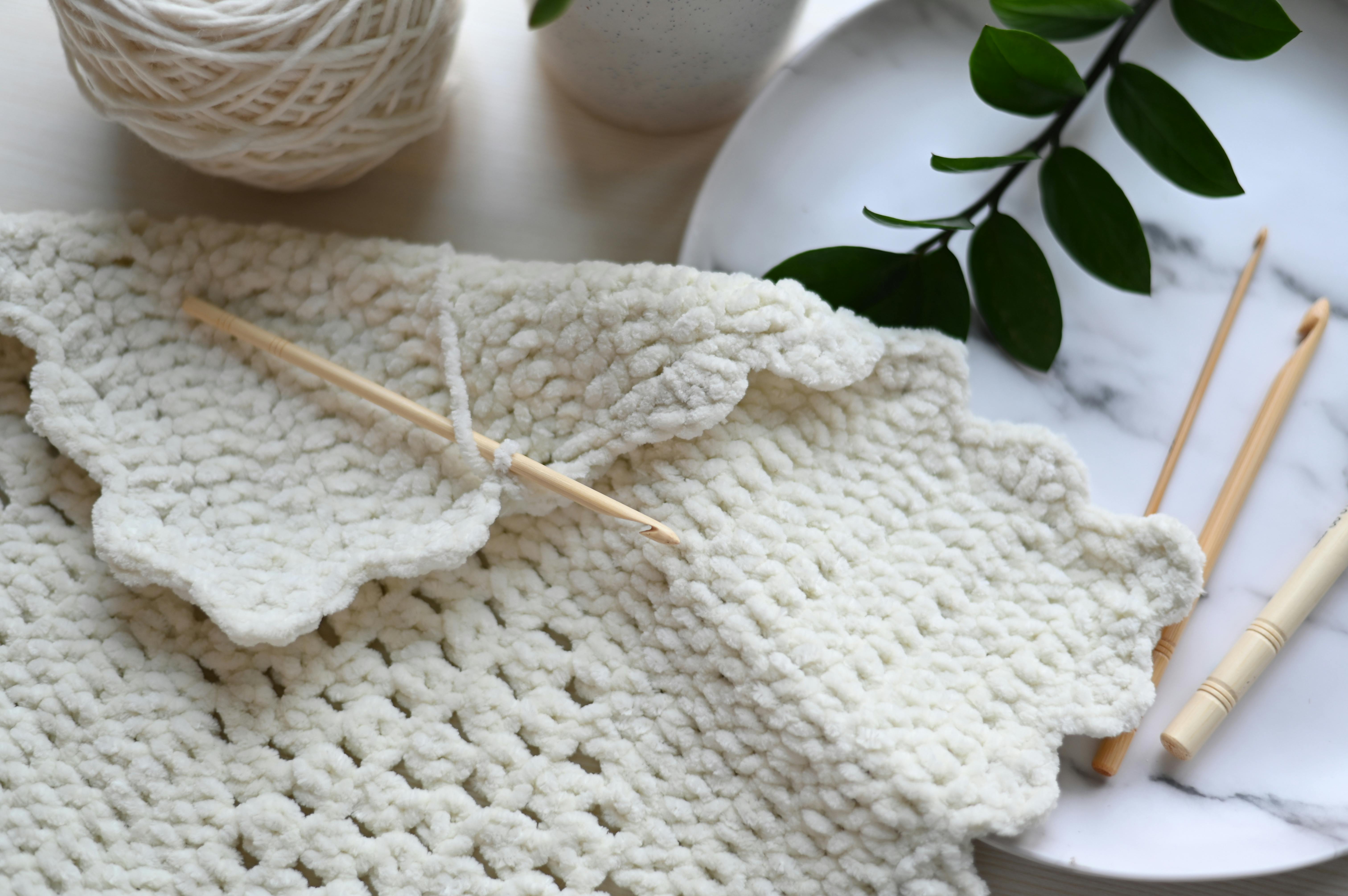 Close-up of crochet project with soft wool yarn and hooks, perfect for crafting enthusiasts.