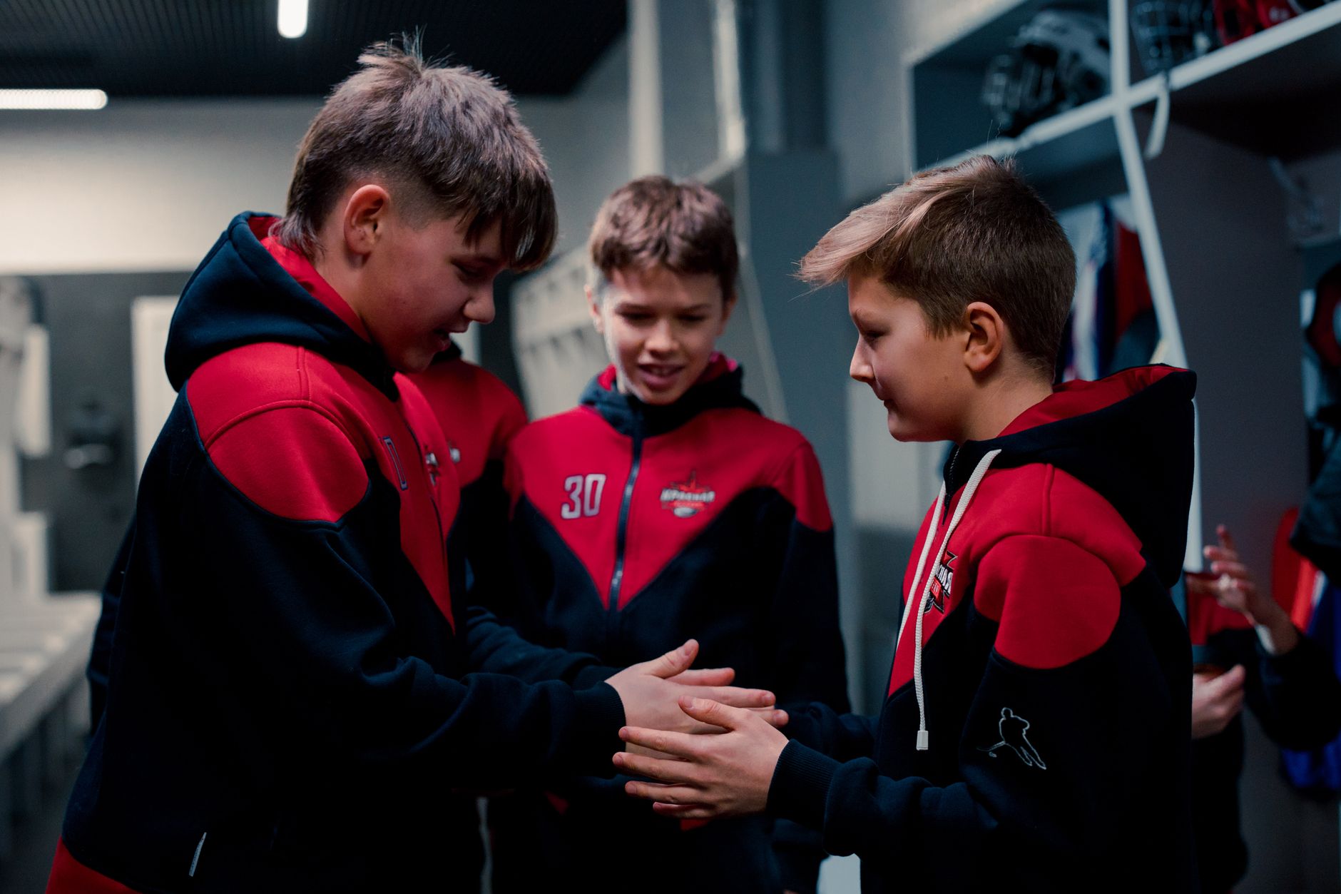 Teen hockey players in a locker room sharing a moment of team spirit.