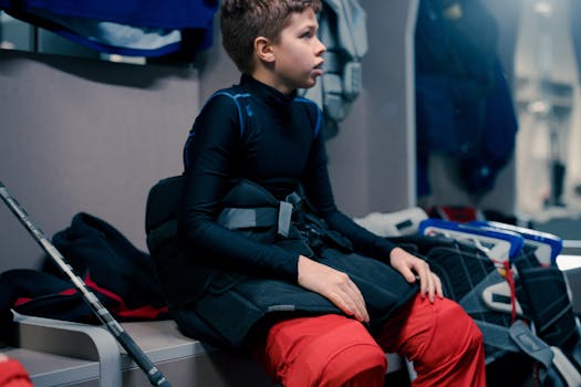 Young athlete in sports gear seated in a locker room, ready for hockey practice.