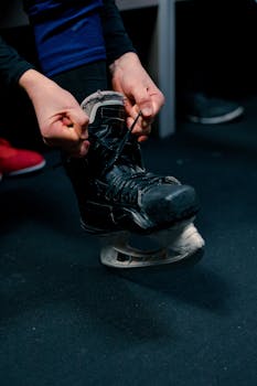 Detailed view of hands tying ice skates, prepping for hockey in a locker room.