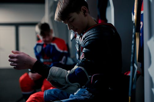 A Boy in the Locker Room Putting on Protective Gears
