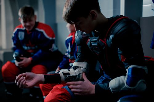 Free Teenage hockey players donning gear in the dressing room before a match. Stock Photo