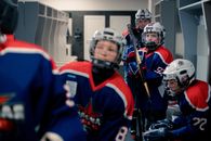 Young hockey team members in gear preparing for a match in the locker room.